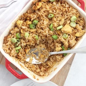 A serving spoon in a dish of egg fried rice.