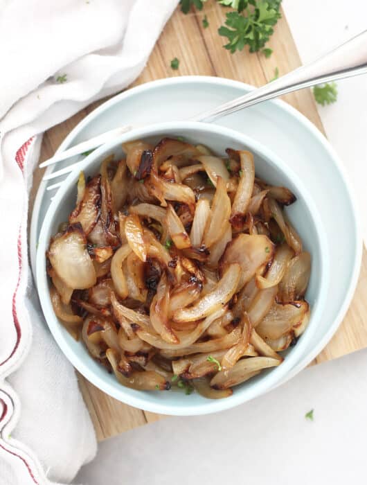Overhead shot of air fryer caramelized onions in a small serving bowl with a fork.