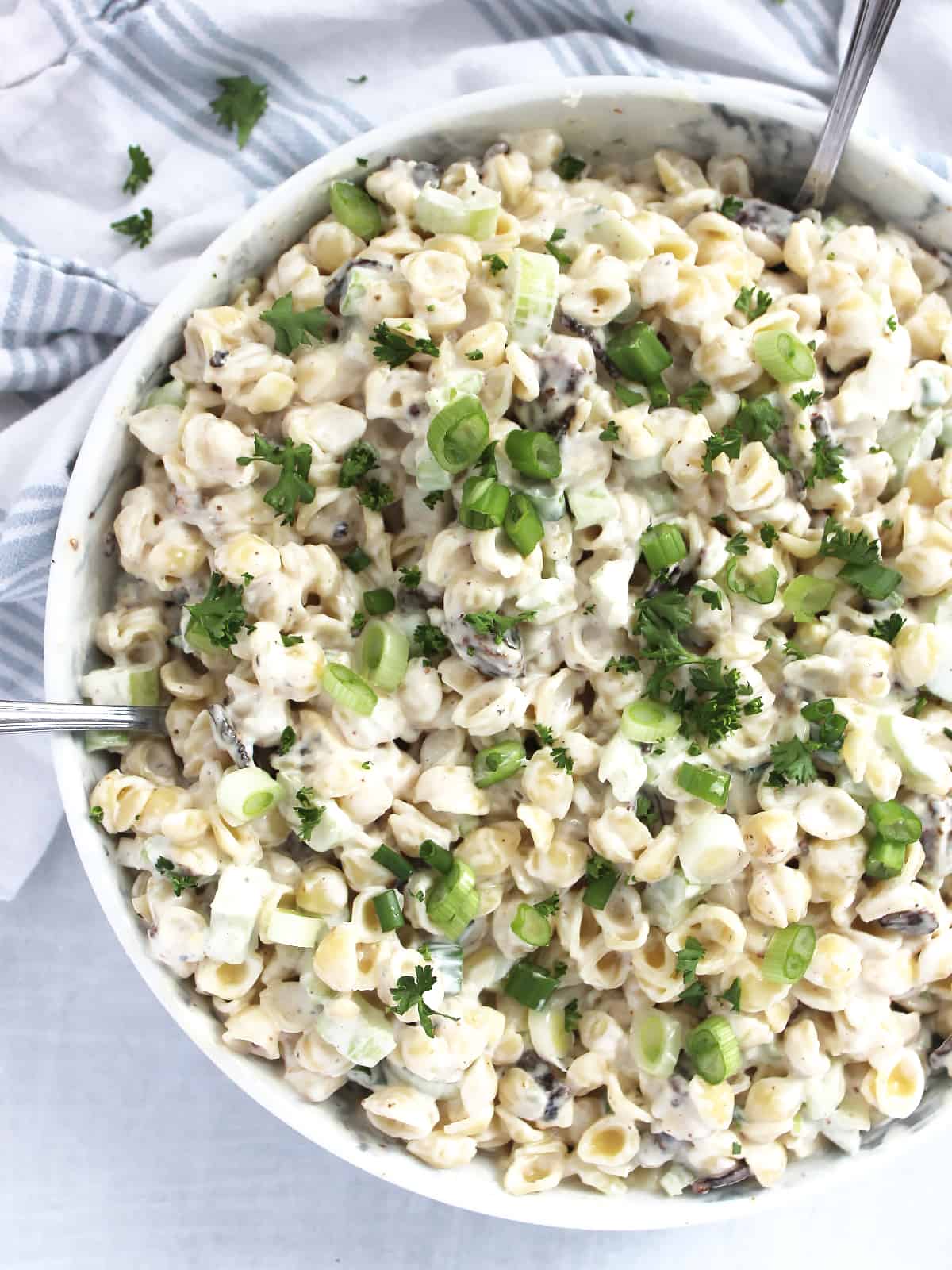 Creamy pasta salad topped with green onions and fresh herbs.
