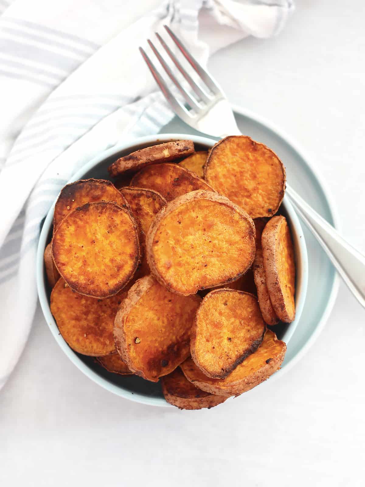 Overjead shot of baked sweet potato slices in a bowl with a fork.