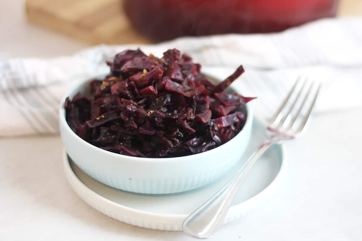 Braised red cabbage in a bowl next to a fork.