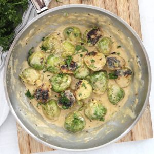 Creamy Brussels sprouts in a skillet garnished with fresh parsley.