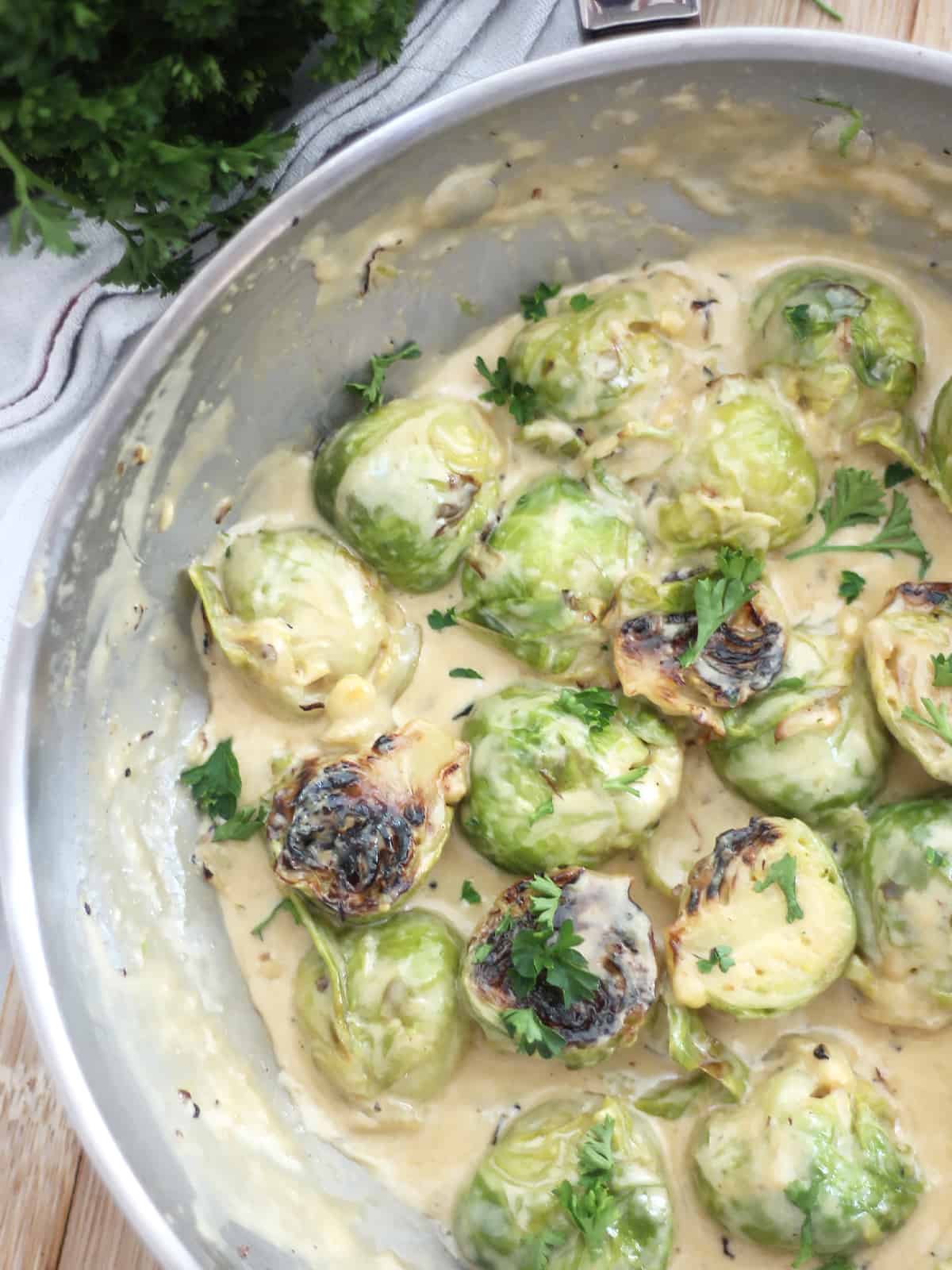 Close up of creamed Brussels sprouts in a silver skillet.