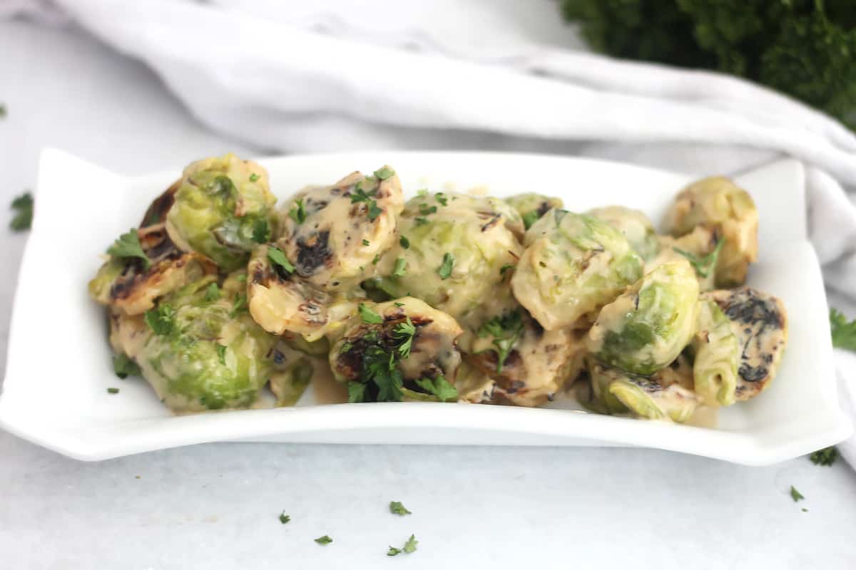 Creamed Brussels sprouts on a white serving dish.