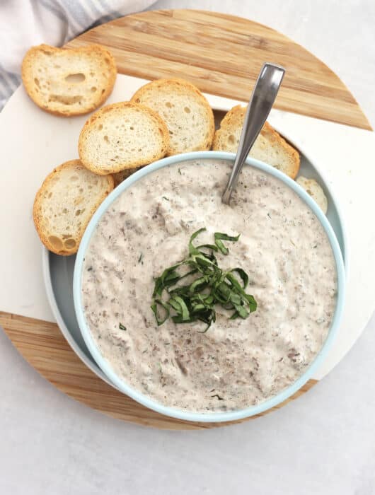 Overhead shot of creamy mushroom dip served with baguette chips.