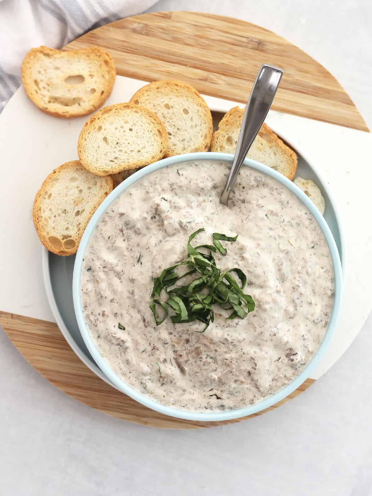 Overhead shot of creamy mushroom dip served with baguette chips.
