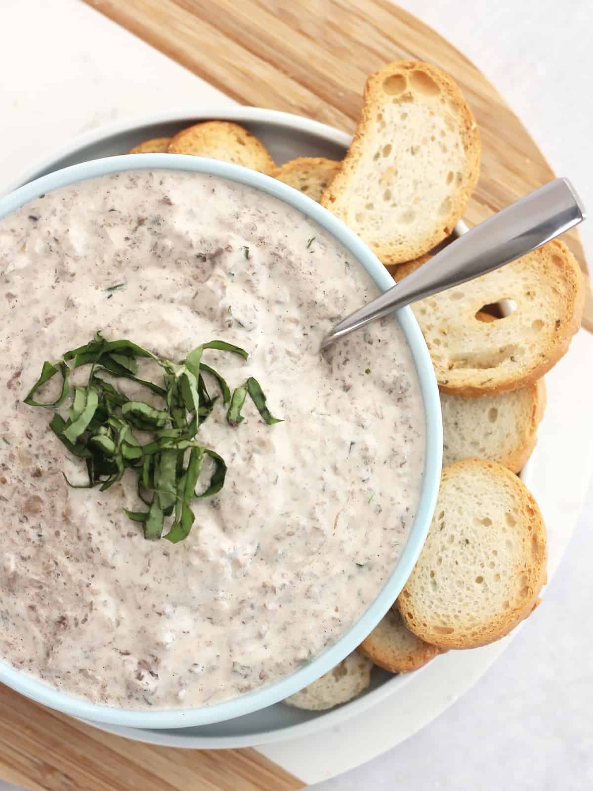 Mushroom dip served in a blue bowl with a spoon.