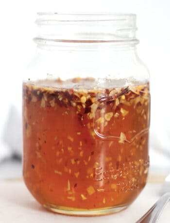 Chili flakes and minced garlic floating in honey in a jar.