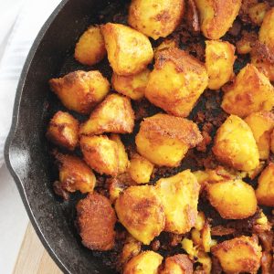 Close up of roasted turmeric potatoes in a cast iron skillet.