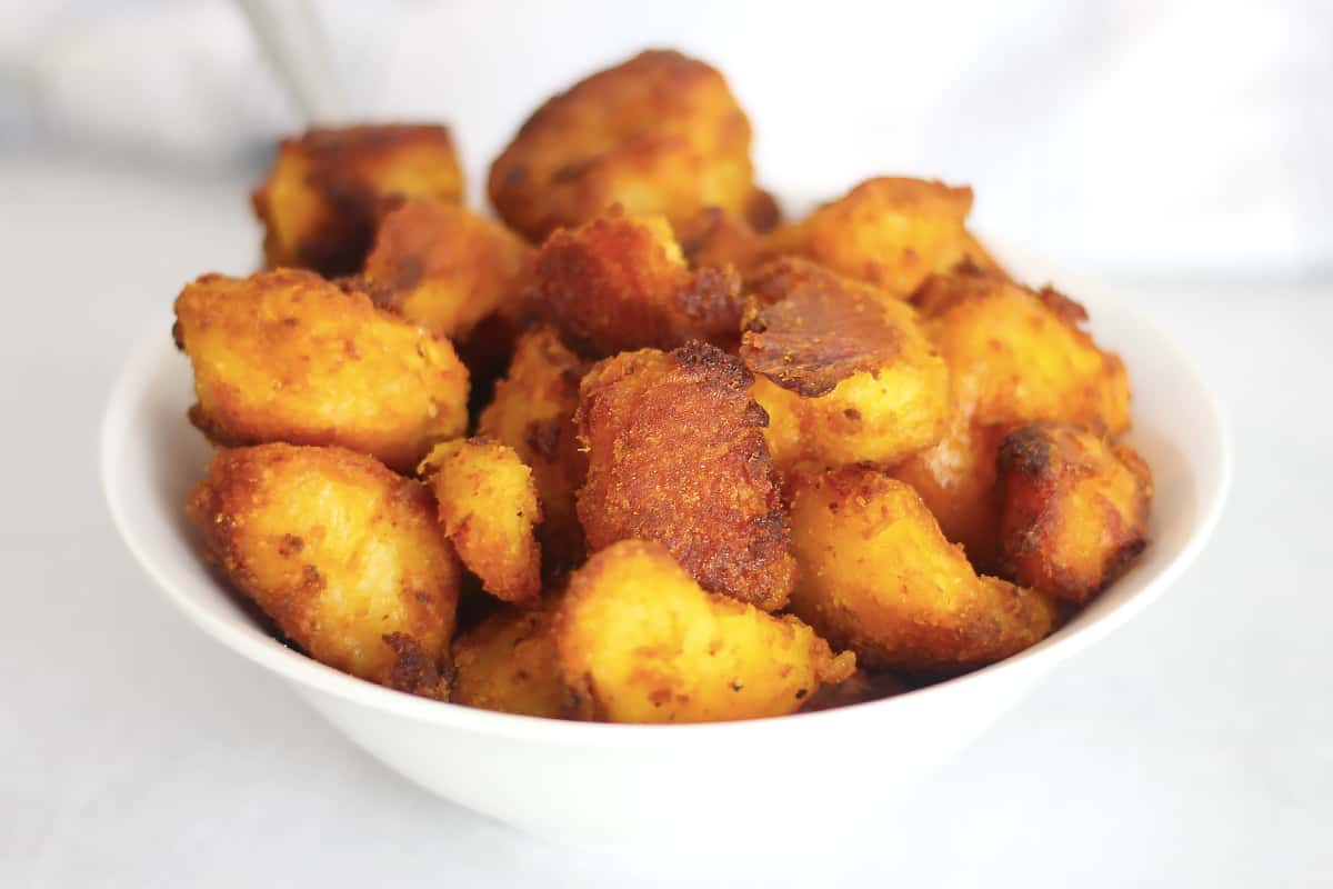 Turmeric roasted potatoes served in a white bowl.