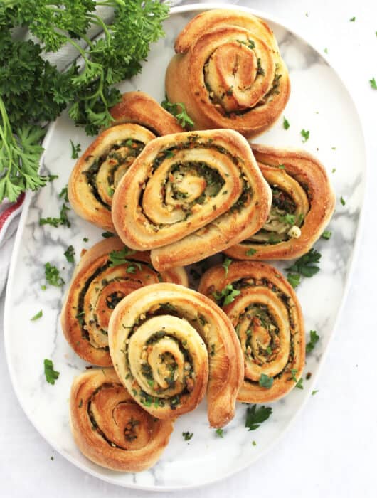 Air fryer garlic pizza rolls stacked on a plate with fresh parsley garnish.