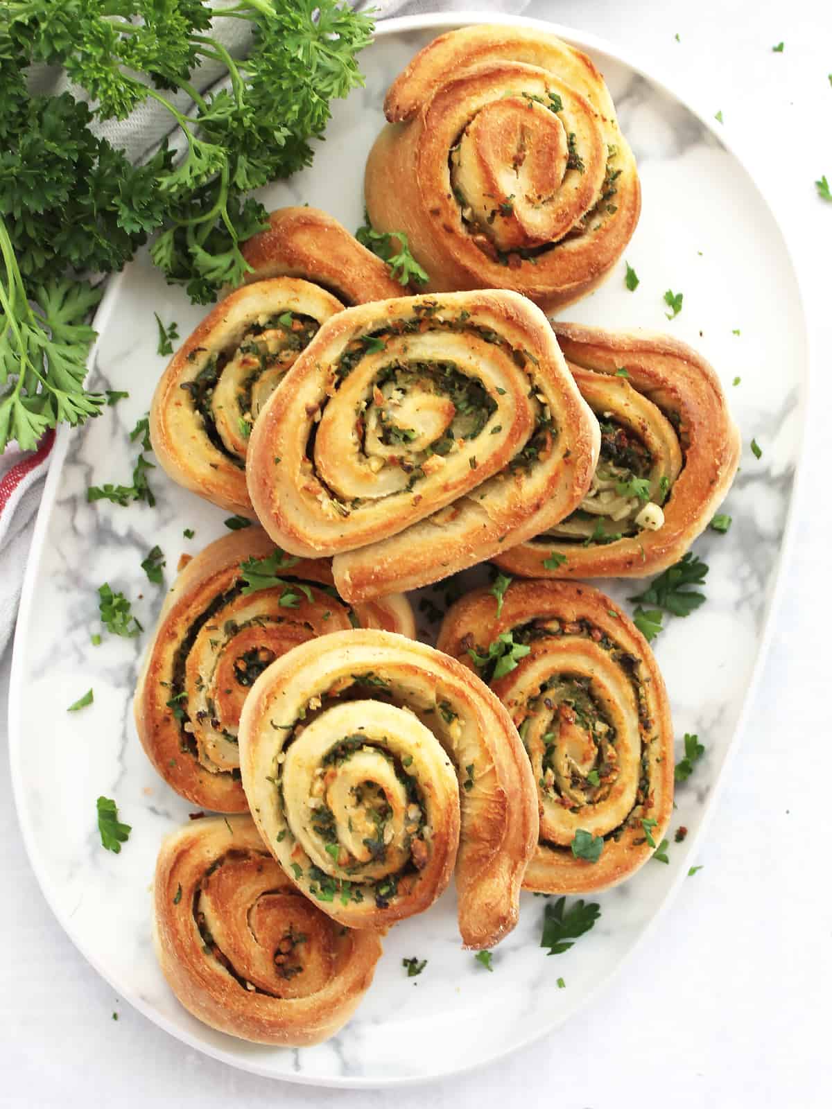 Air fryer garlic pizza rolls stacked on a plate with fresh parsley garnish.