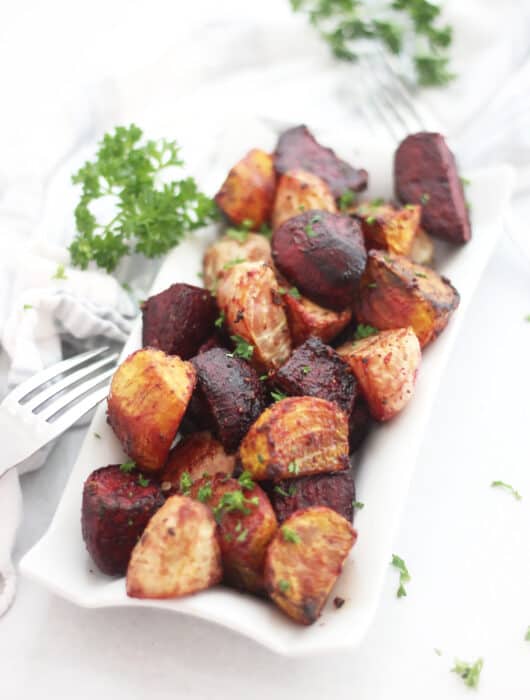 Roasted beetroots on a plate next to a fork.