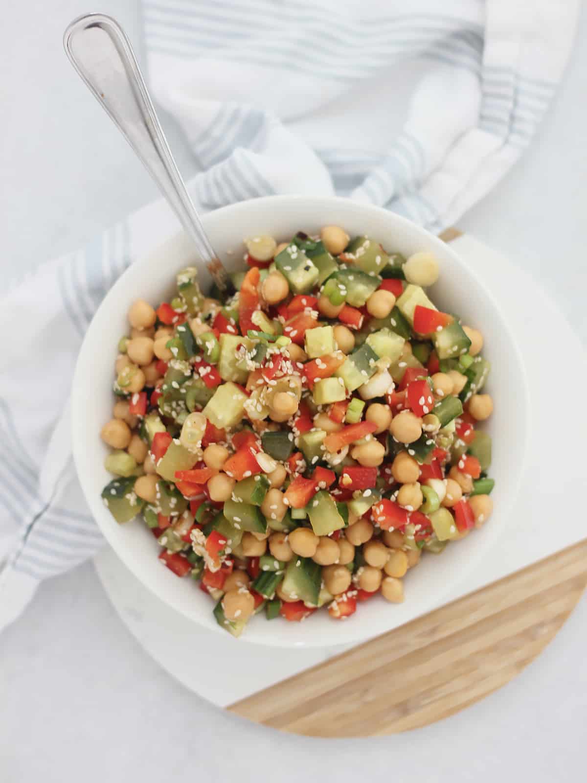 Overhead shot of Asian chickpea and cucumber salad in a white bowl with a spoon.