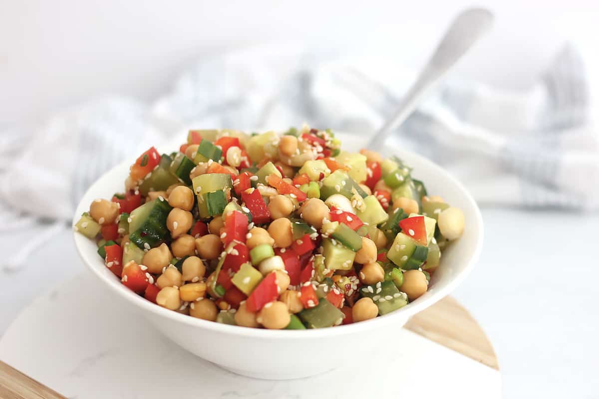 Asian chickpea salad in a white bowl with a spoon.