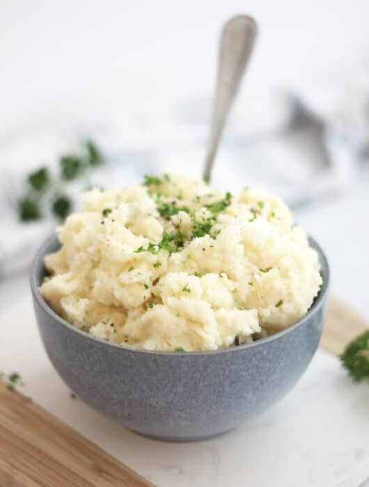 Boursin mashed potatoes in a blue bowl with a spoon.