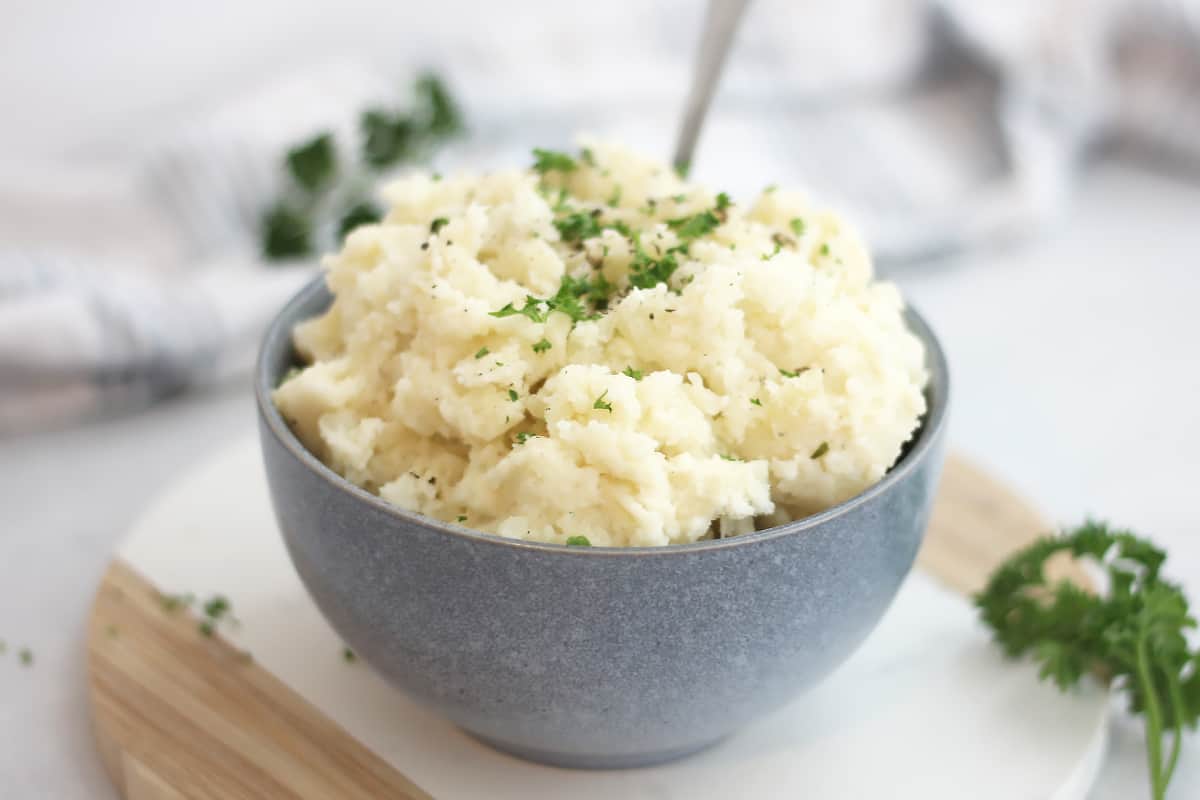 Boursin mashed potatoes in a blue bowl with fresh parsley garnish.