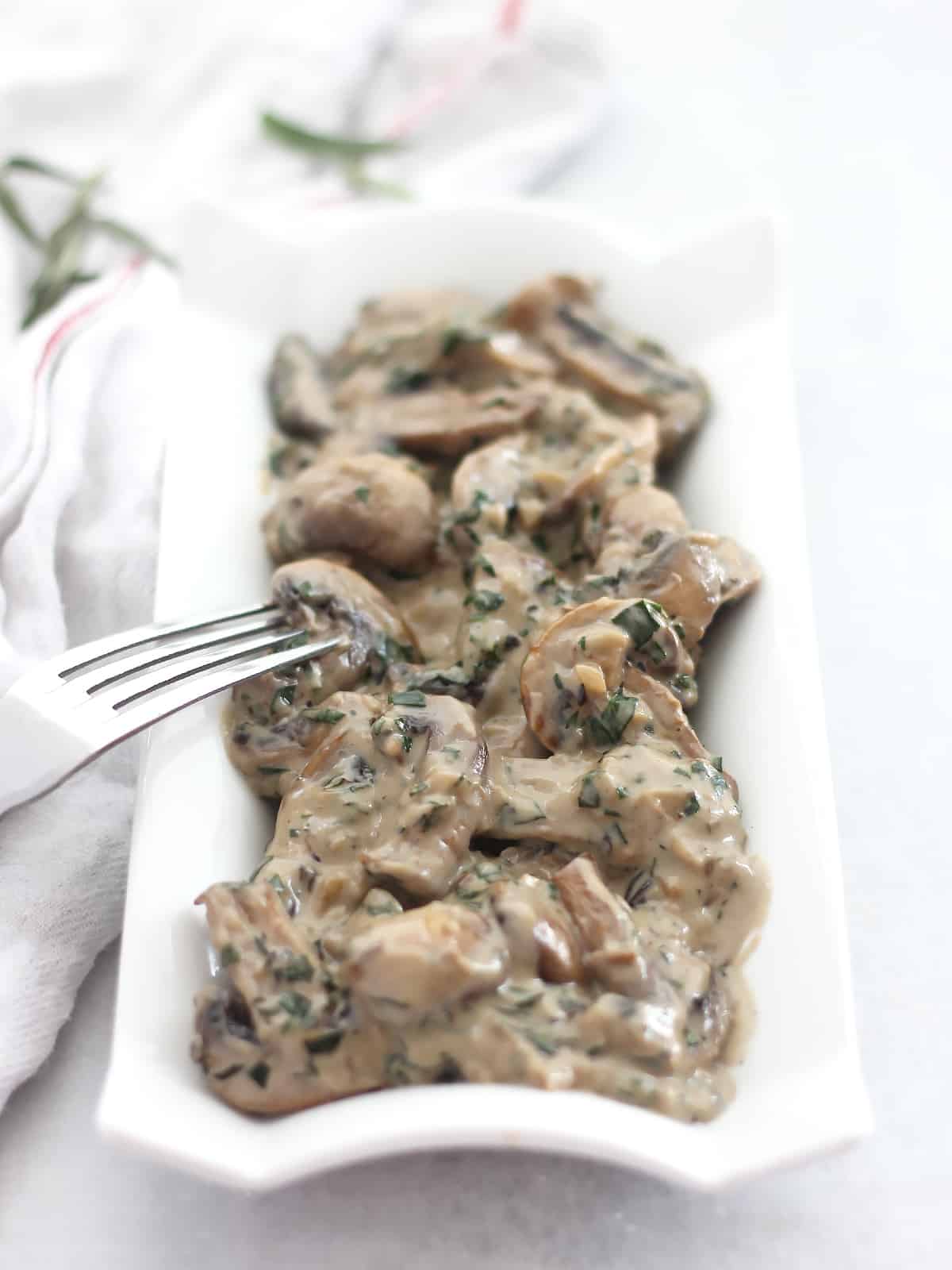 Mushrooms and cream sauce served on a long white plate.