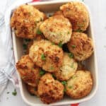 Crispy mashed potato balls in a serving dish garnished with fresh parsley.