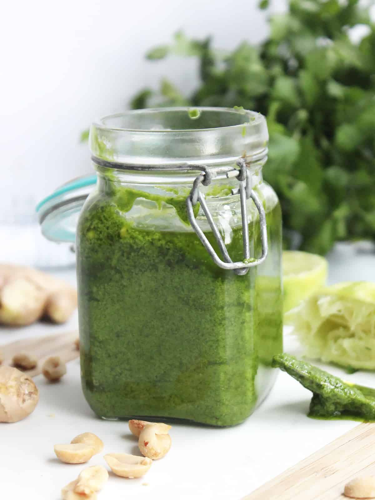 A jar of Asian pesto in front of a bunch of fresh cilantro.