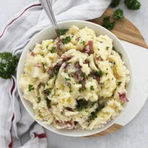 Red skinned mashed potatoes in a bowl garnished with fresh parsley.