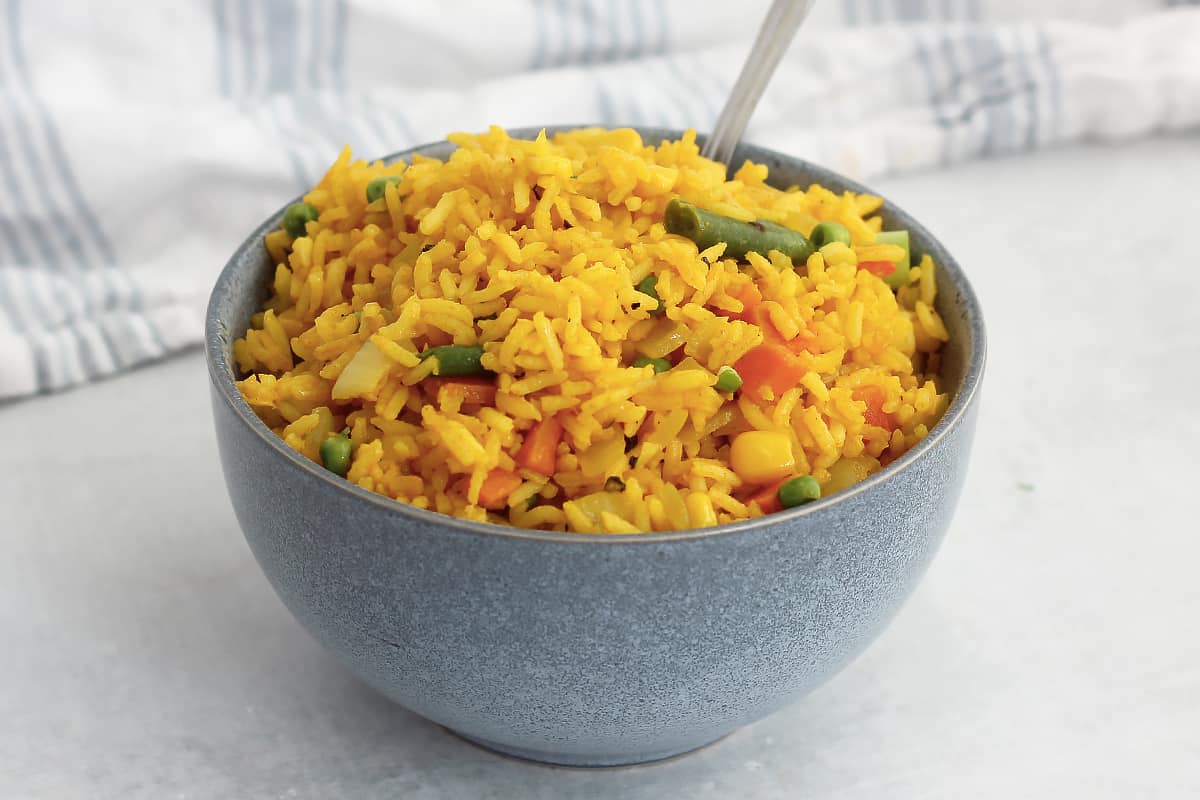 Turmeric fried rice and vegetables in a blue bowl.