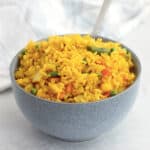 Turmeric rice in a blue bowl with a spoon.