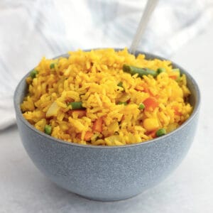 Turmeric rice in a blue bowl with a spoon.