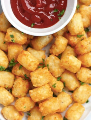 Overhead shot of air fried tater tots next to a bowl of ketchup.