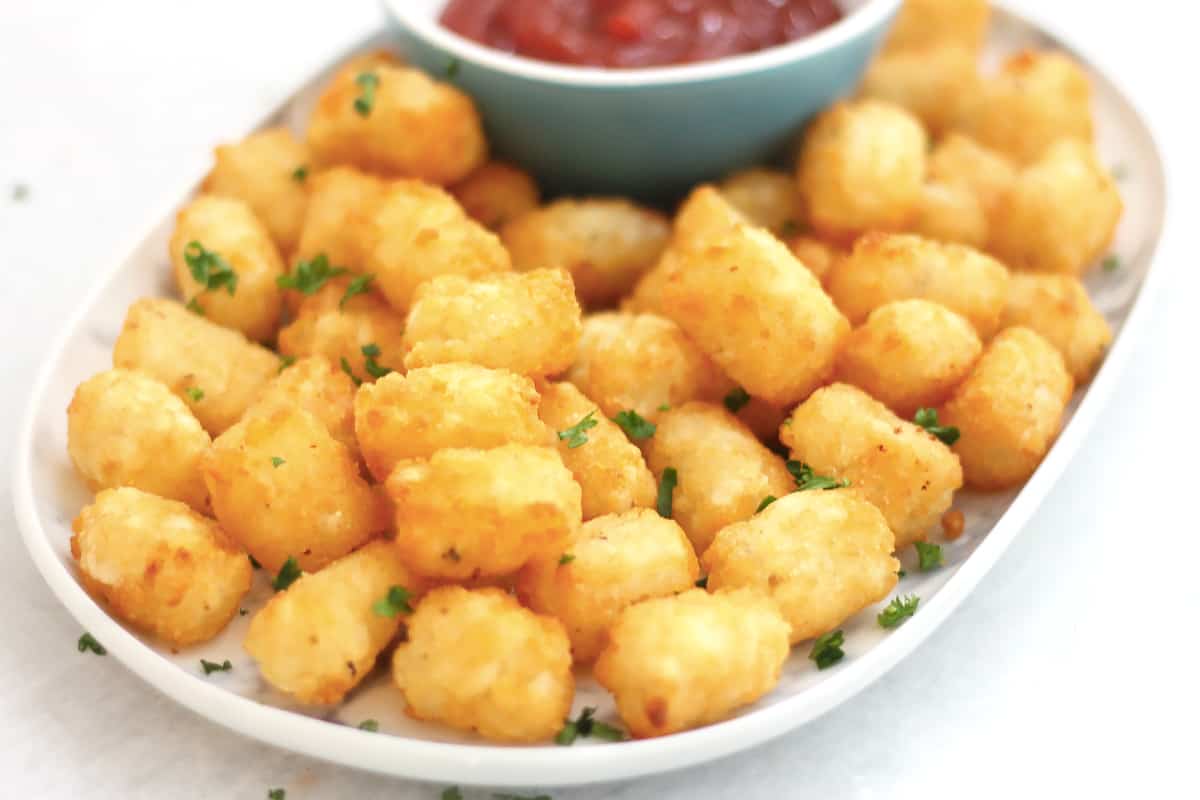 Golden brown tater tots on a plate garnished with fresh parsley.