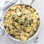 Cajun potato and egg salad in a serving bowl with two spoons.
