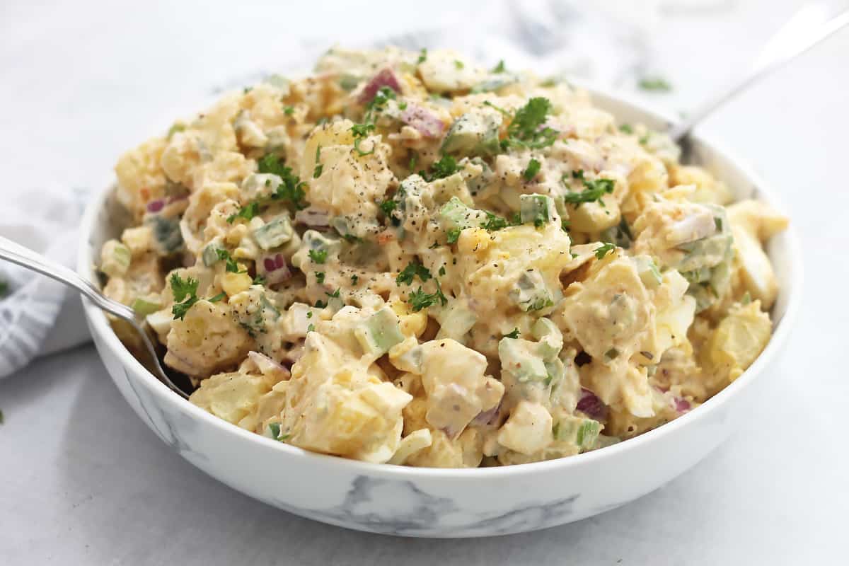 Creamy potato salad in a bowl and garnished with fresh parsley.