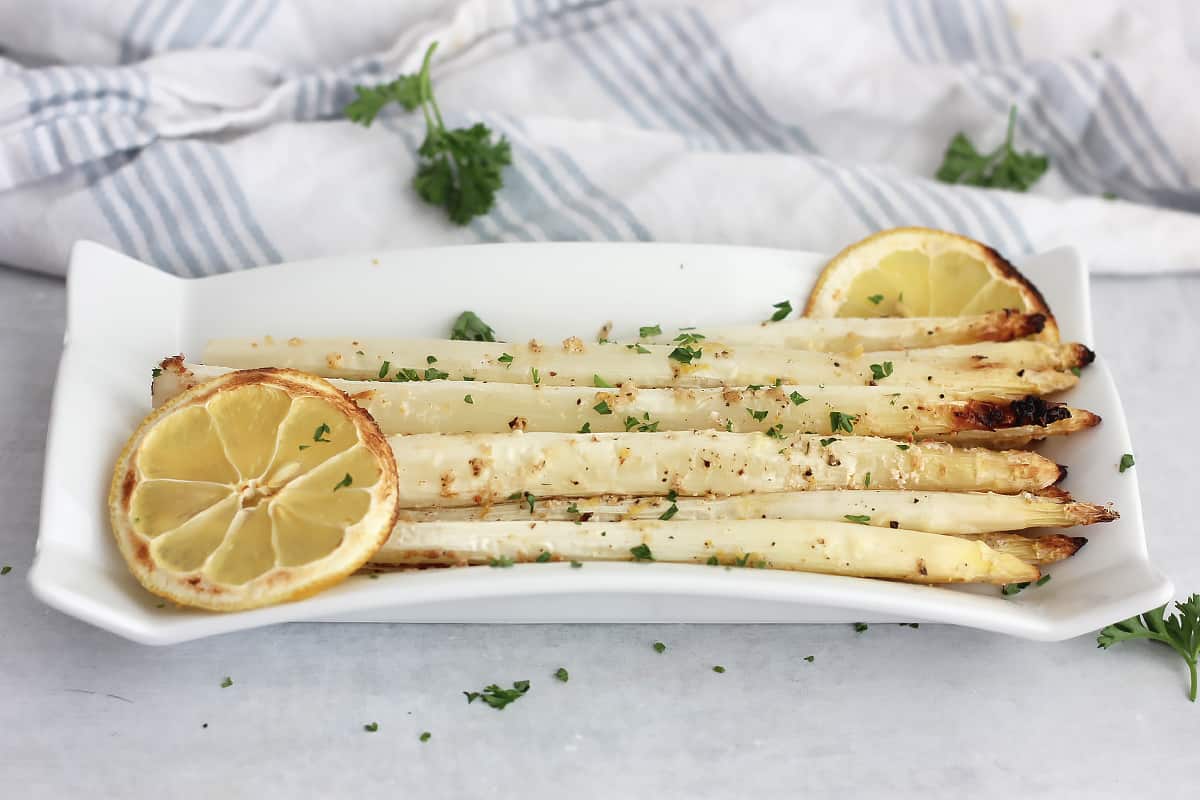 Roasted lemon and parmesan white asparagus on a long serving plate.