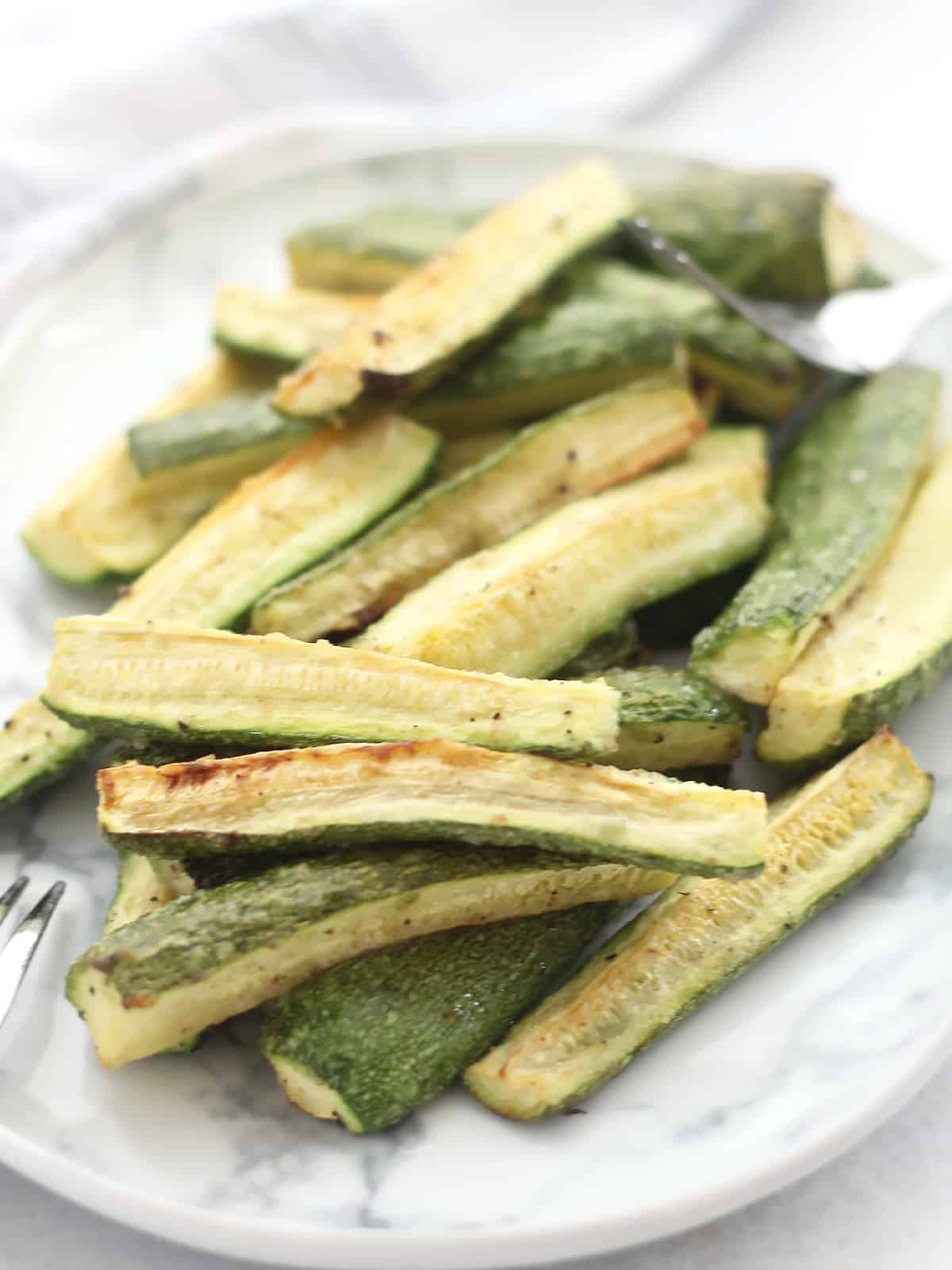 Roasted zucchini spears served on a plate.