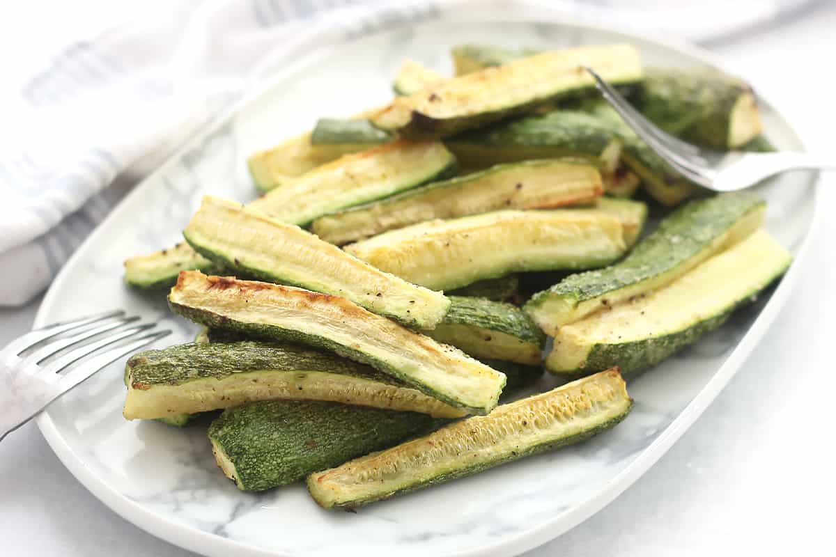 White zucchini spears served on a plate with two forks.