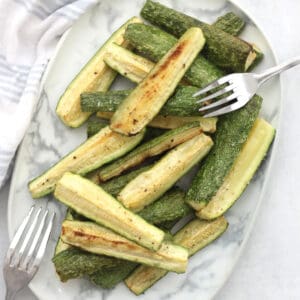 Roasted white zucchini spears on a serving plate.