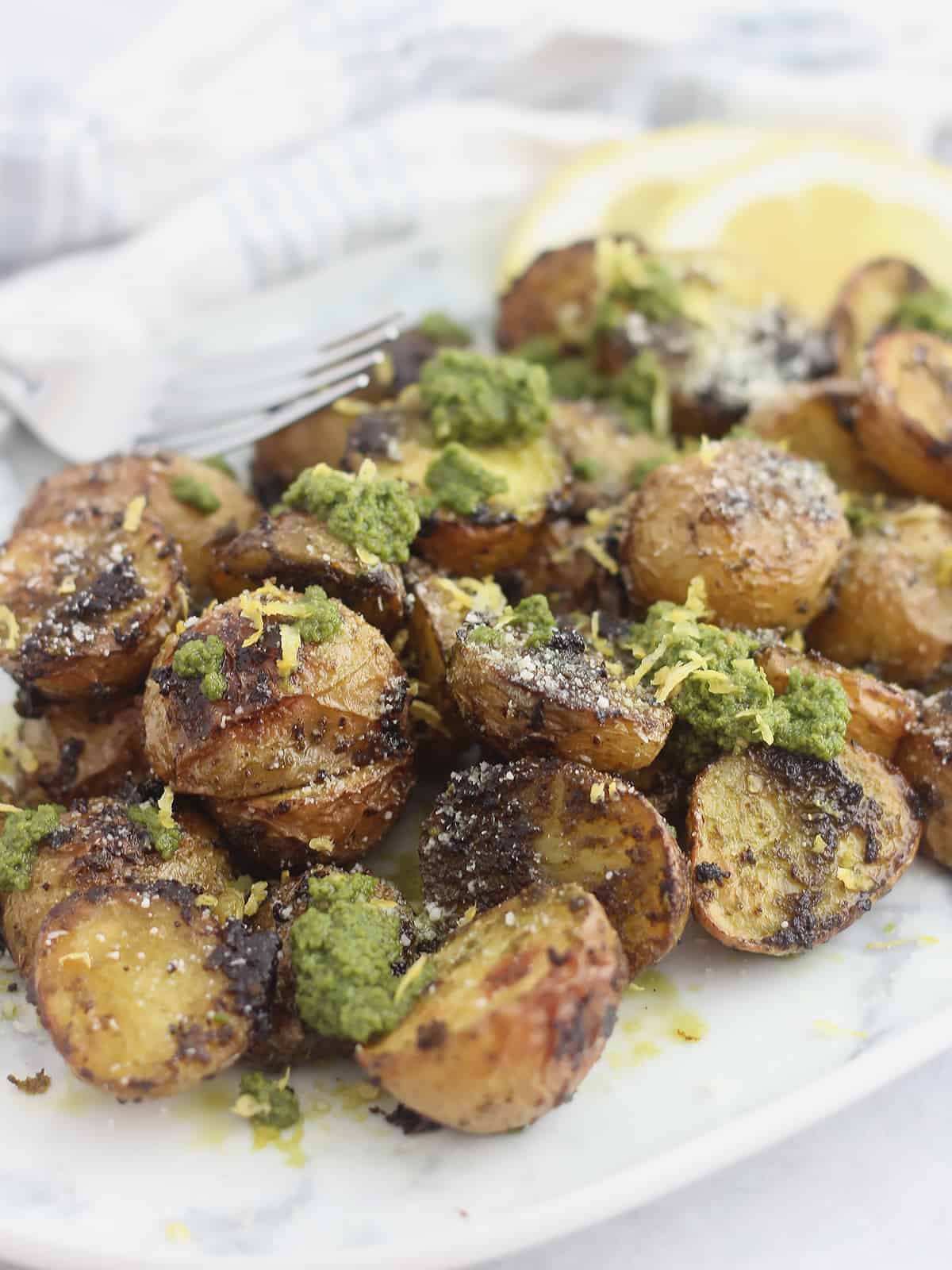 Roasted baby potatoes on a serving plate with lemon slices.