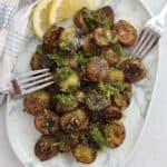 Roasted pesto baby potatoes on a serving plate with two forks.