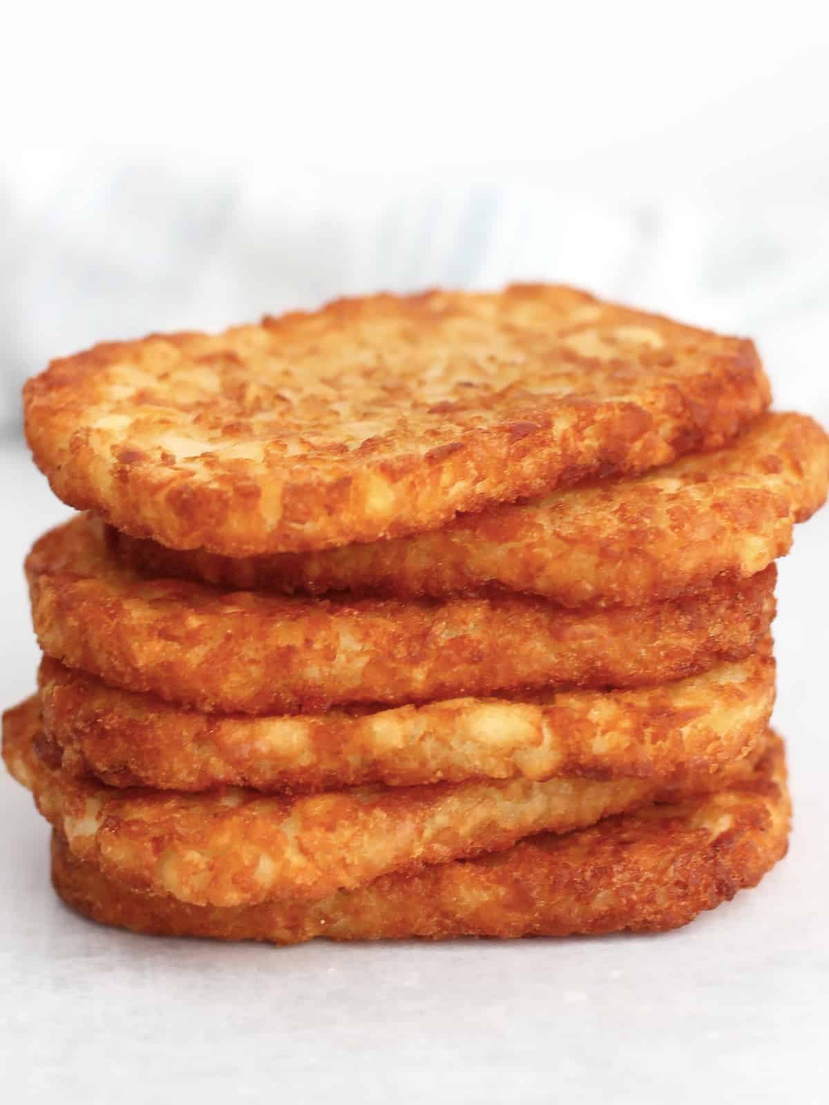 Close up of six crispy hash browns stacked on top of each other.
