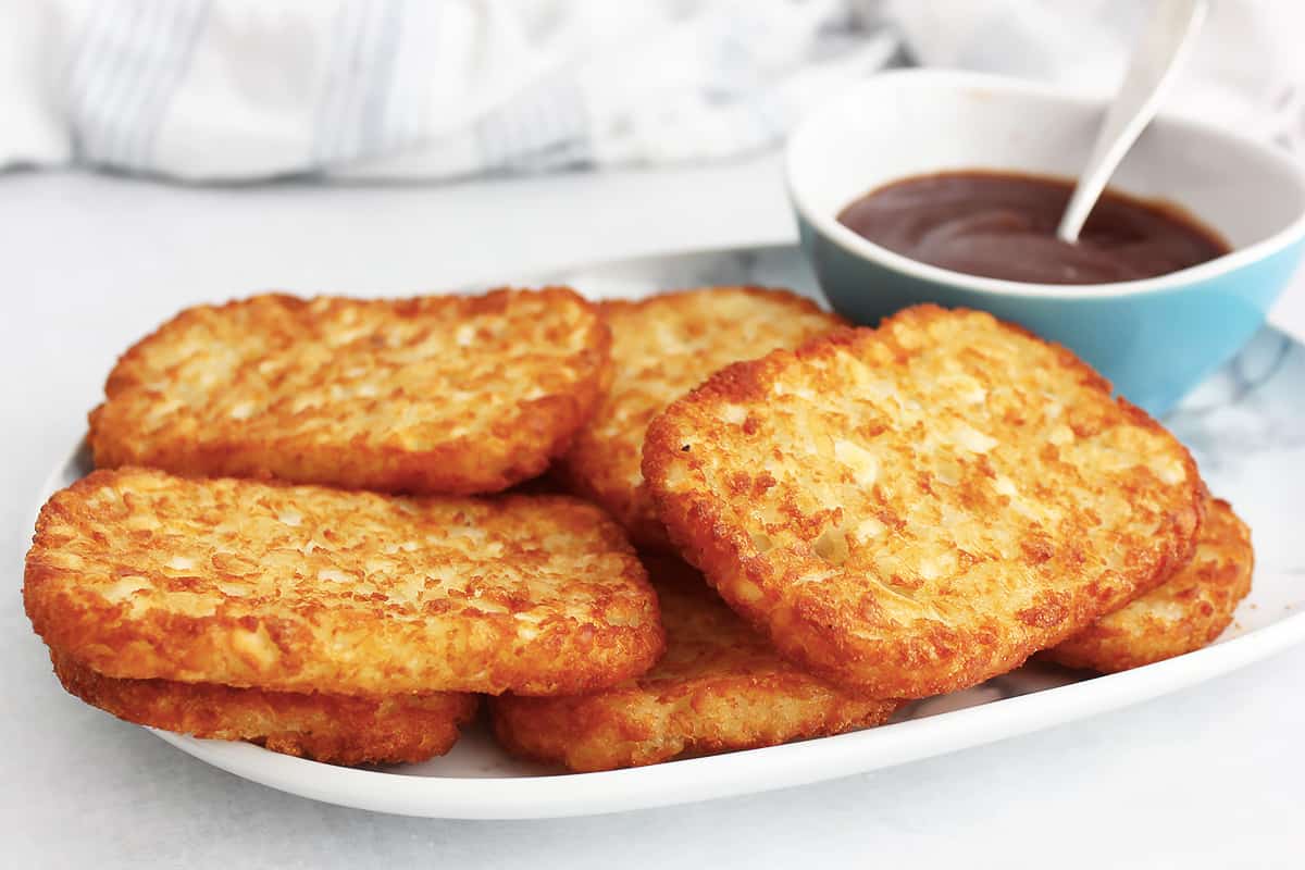 Air fryer frozen hash browns piled on a serving plate.