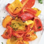 Roasted bell peppers on a plate garnished with fresh parsley.