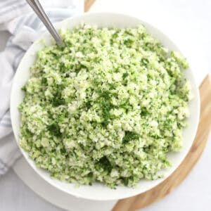 Broccoli cauliflower rice in a white bowl with a spoon.