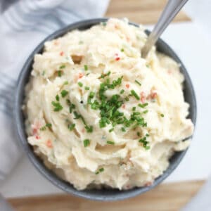 Mashed potato salad in a bowl garnished with freshly chopped chives.