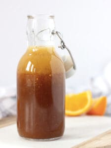Orange salad dressing in a glass bottle with a stopper.