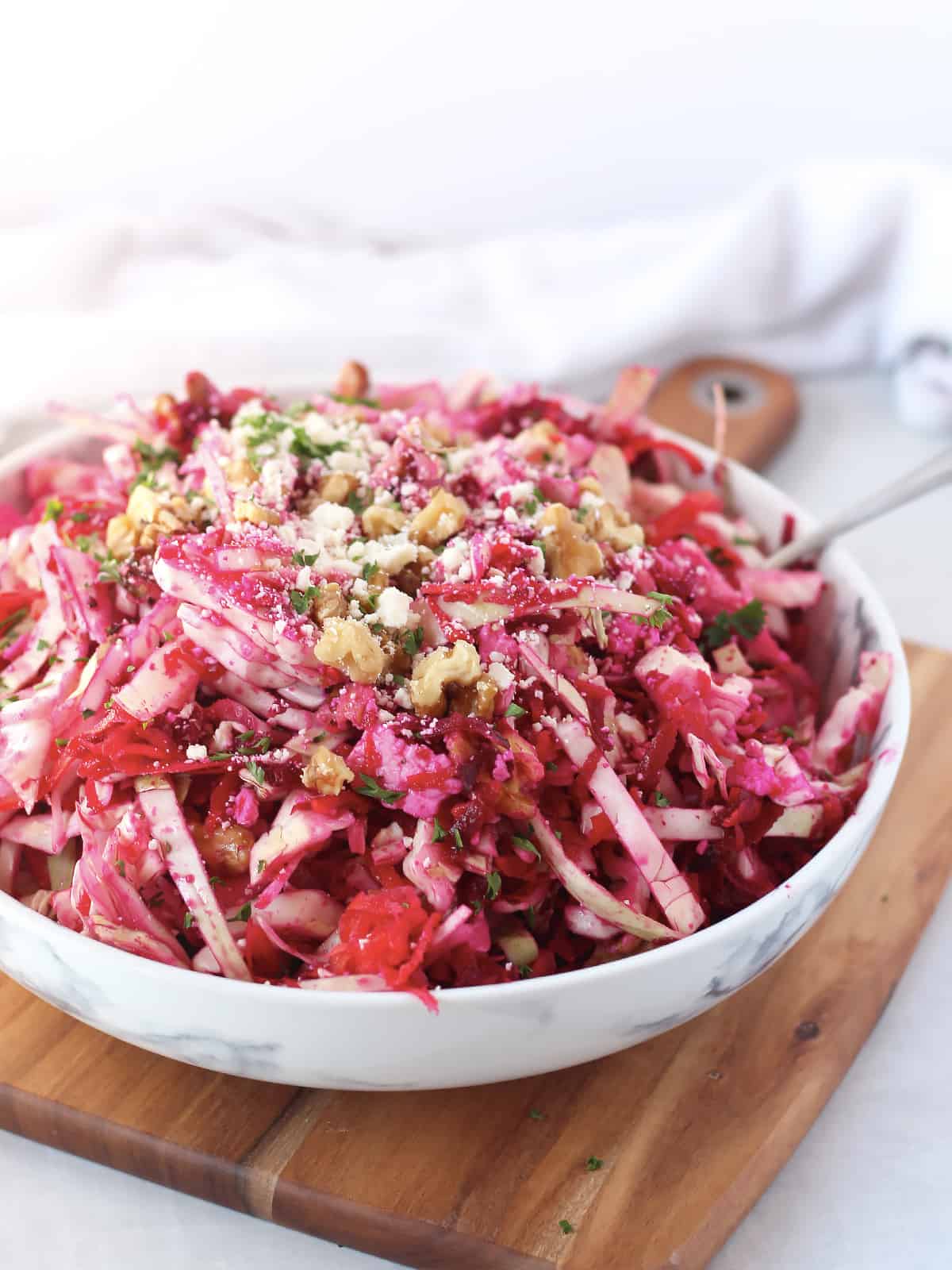 A large bowl of slaw on a wooden board.
