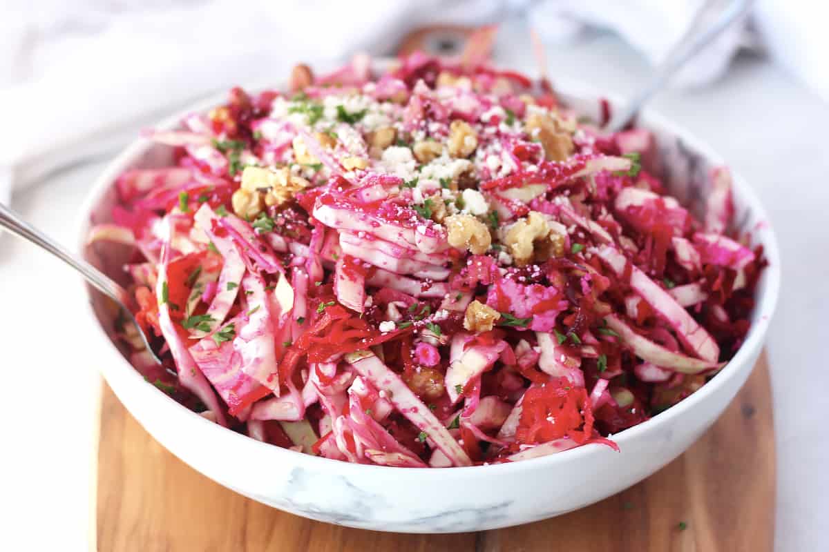 Beet slaw in a serving bowl on a wooden board.
