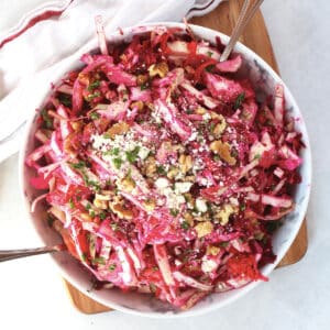 Beet, cabbage and carrot slaw in a bowl with two spoons.