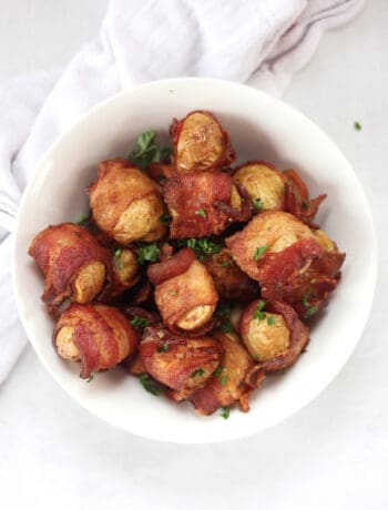 Air fried bacon wrapped potatoes in a serving bowl and garnished with parsley.