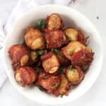 Crispy bacon wrapped potatoes in a bowl garnished with fresh parsley.