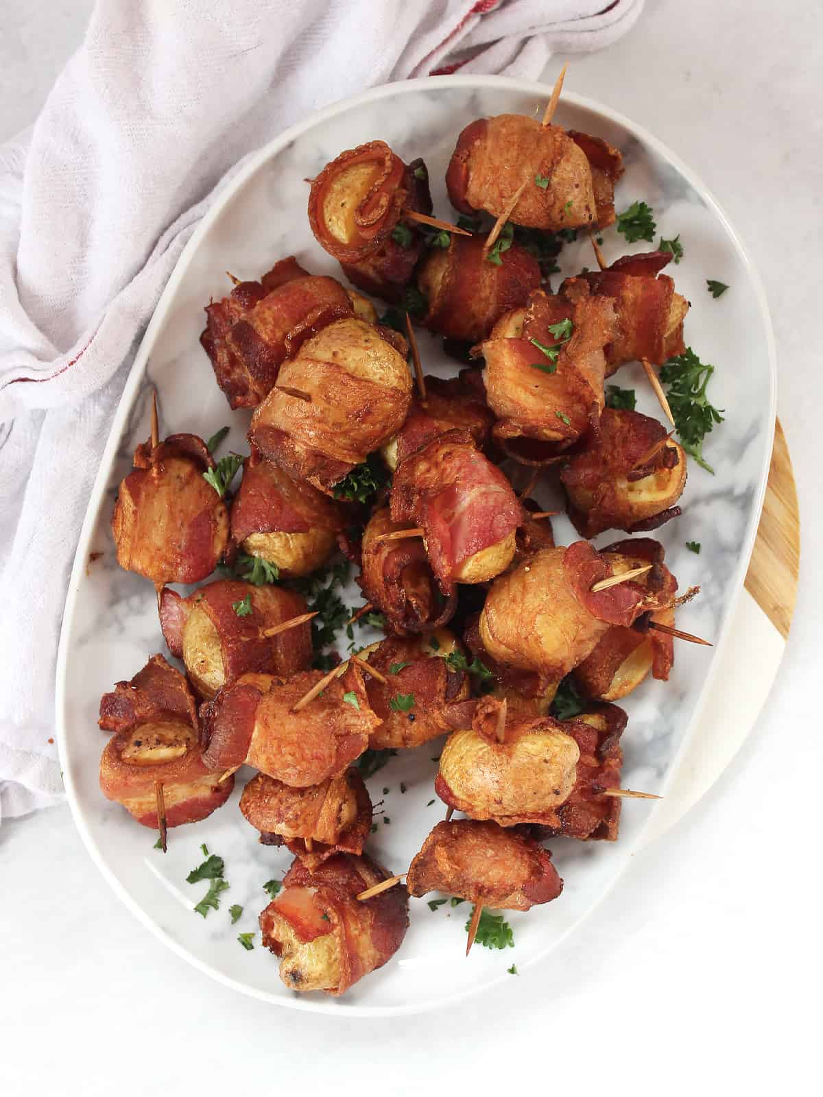 Bacon wrapped potatoes served on a plate with toothpicks as an appetizer.
